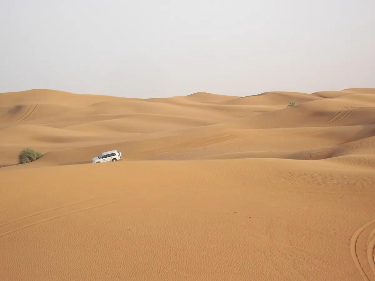 A 4x4 between wide sand dunes near Dubai